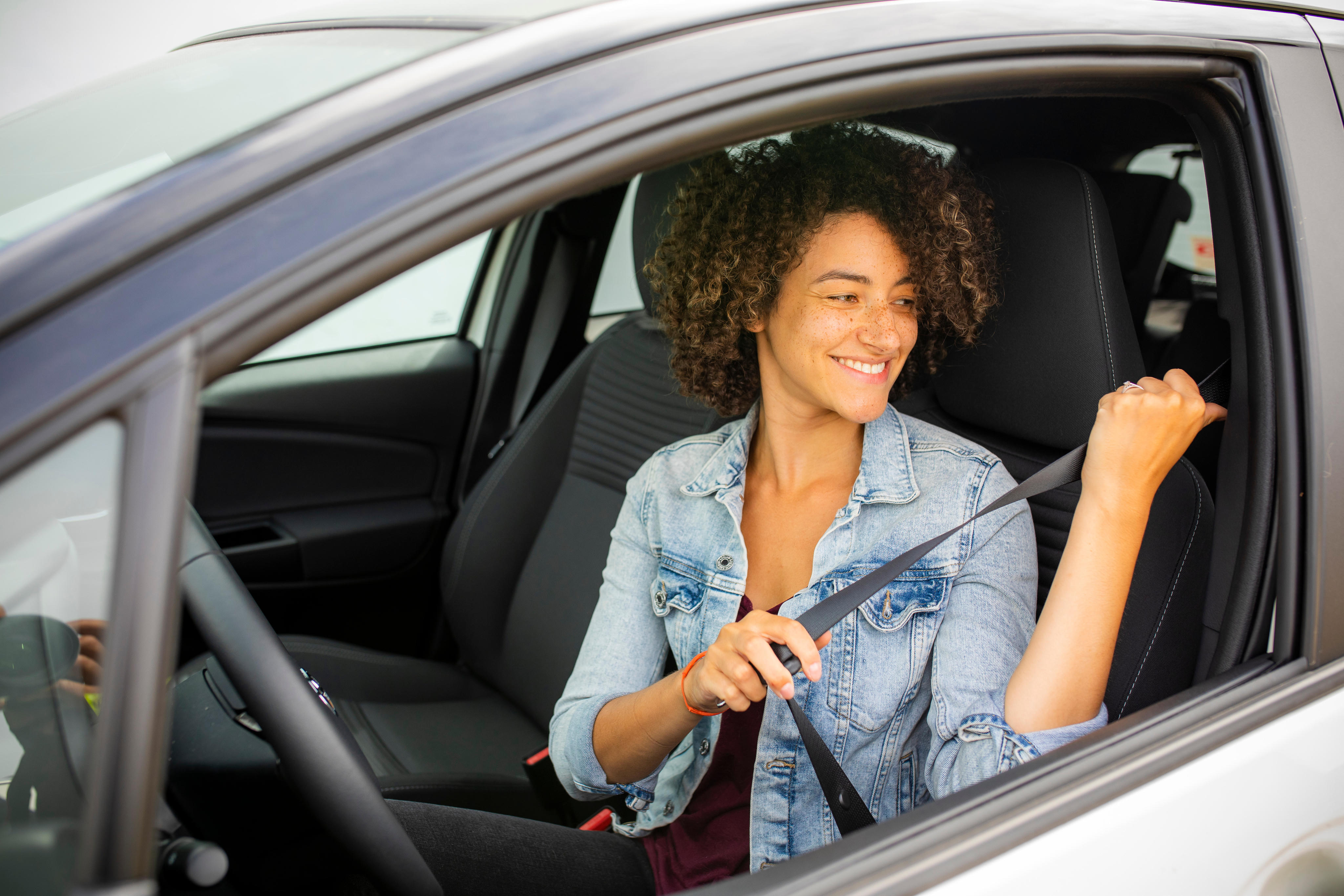 A teen driver buckles their seatbelt