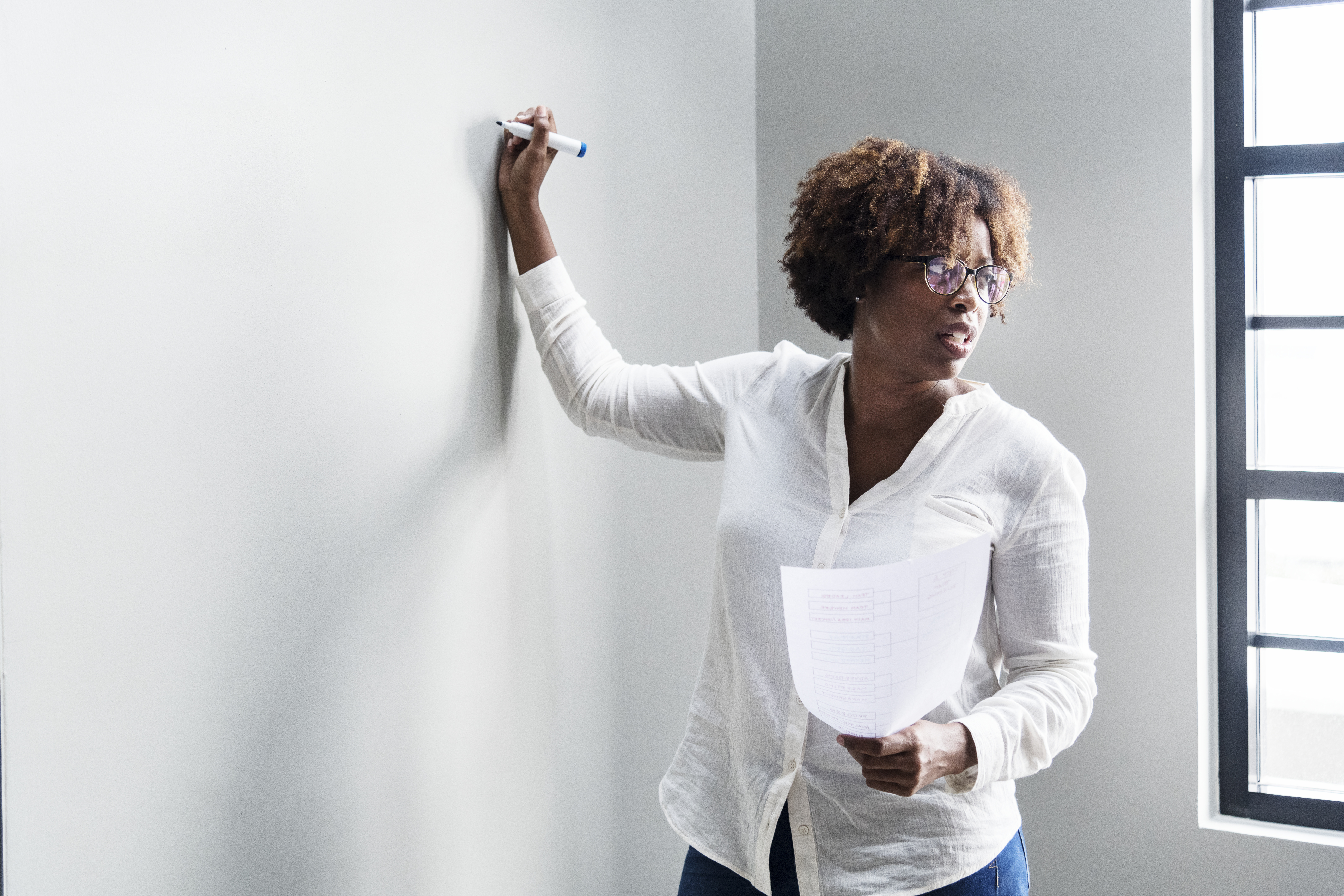 A woman writing on a whiteboard in an office